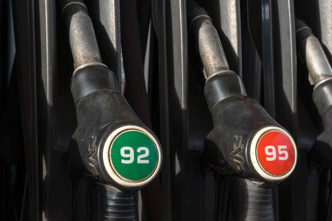 A row of fuel pump nozzles labelled with different fuel grades, including 92 and 95 octane