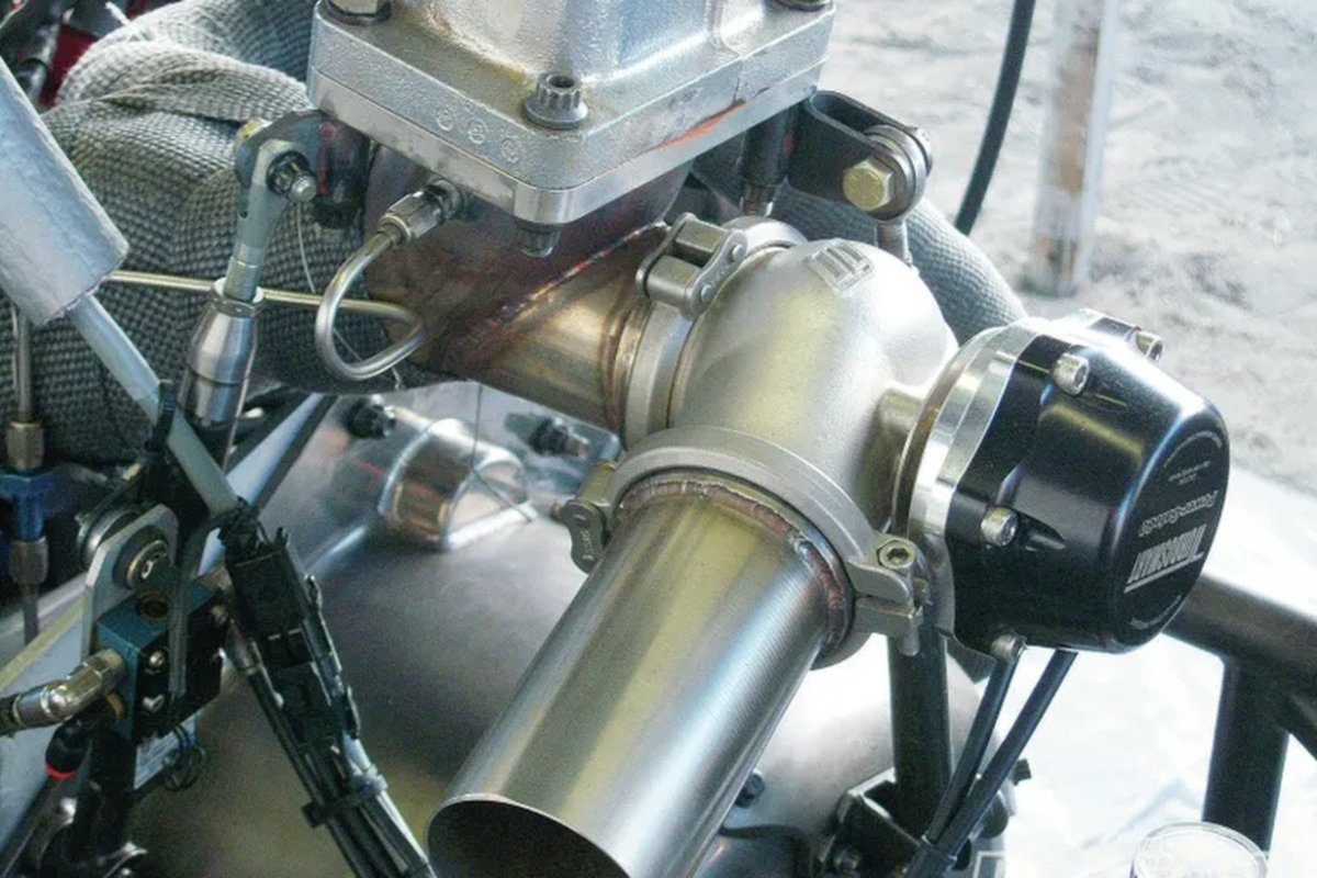 An external wastegate mounted at the exhaust manifold collector alongside the turbocharger turbine housing, with the dump pipe running off the valve body