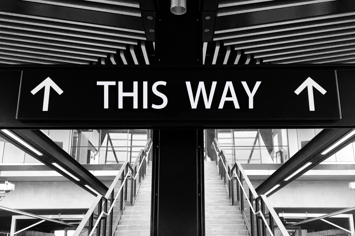 A black and white THIS WAY sign with upward arrows above a staircase, marking where to start with EFI tuning